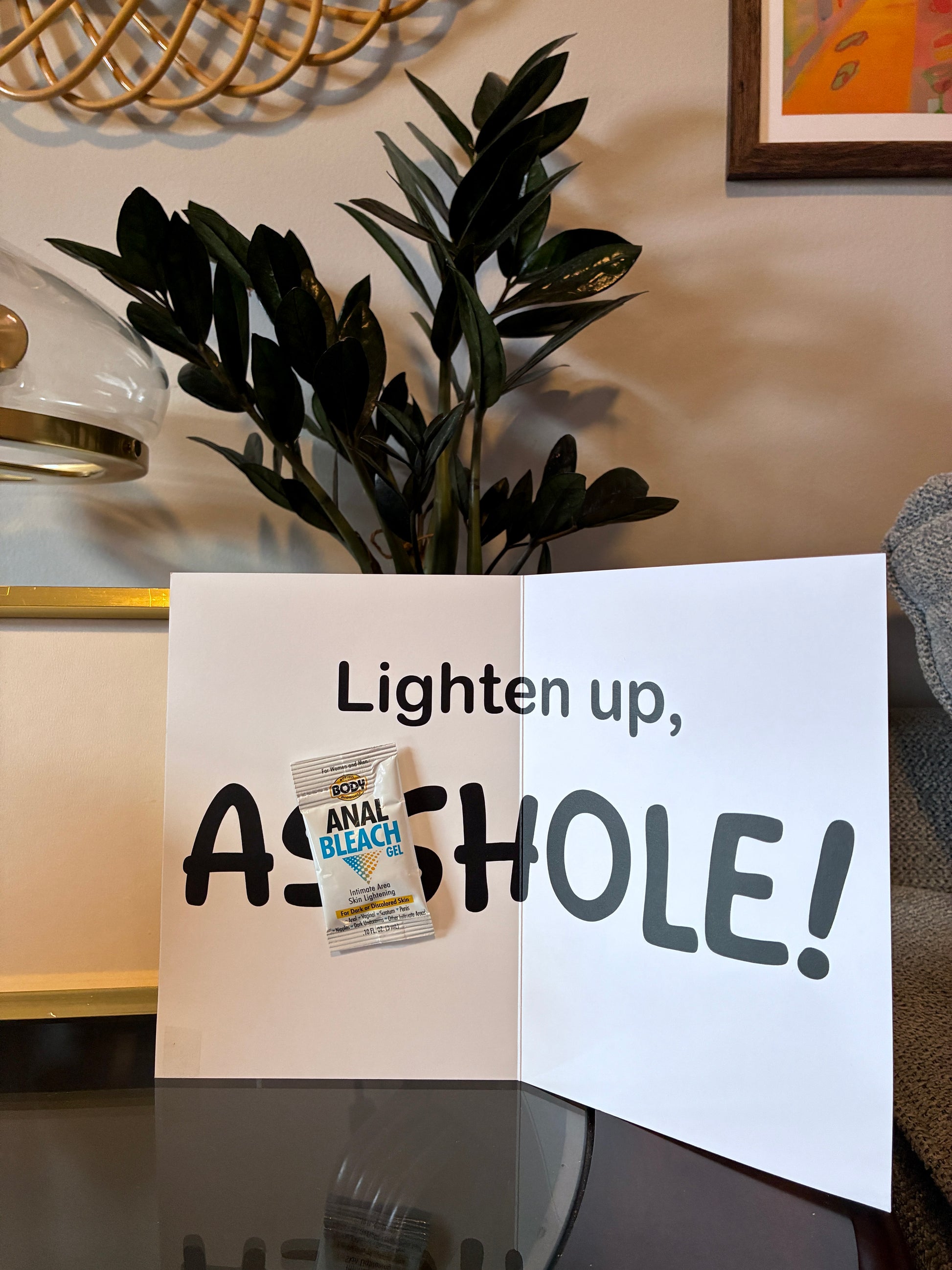 Greeting card shown in cozy indoor setting next to decor and plants